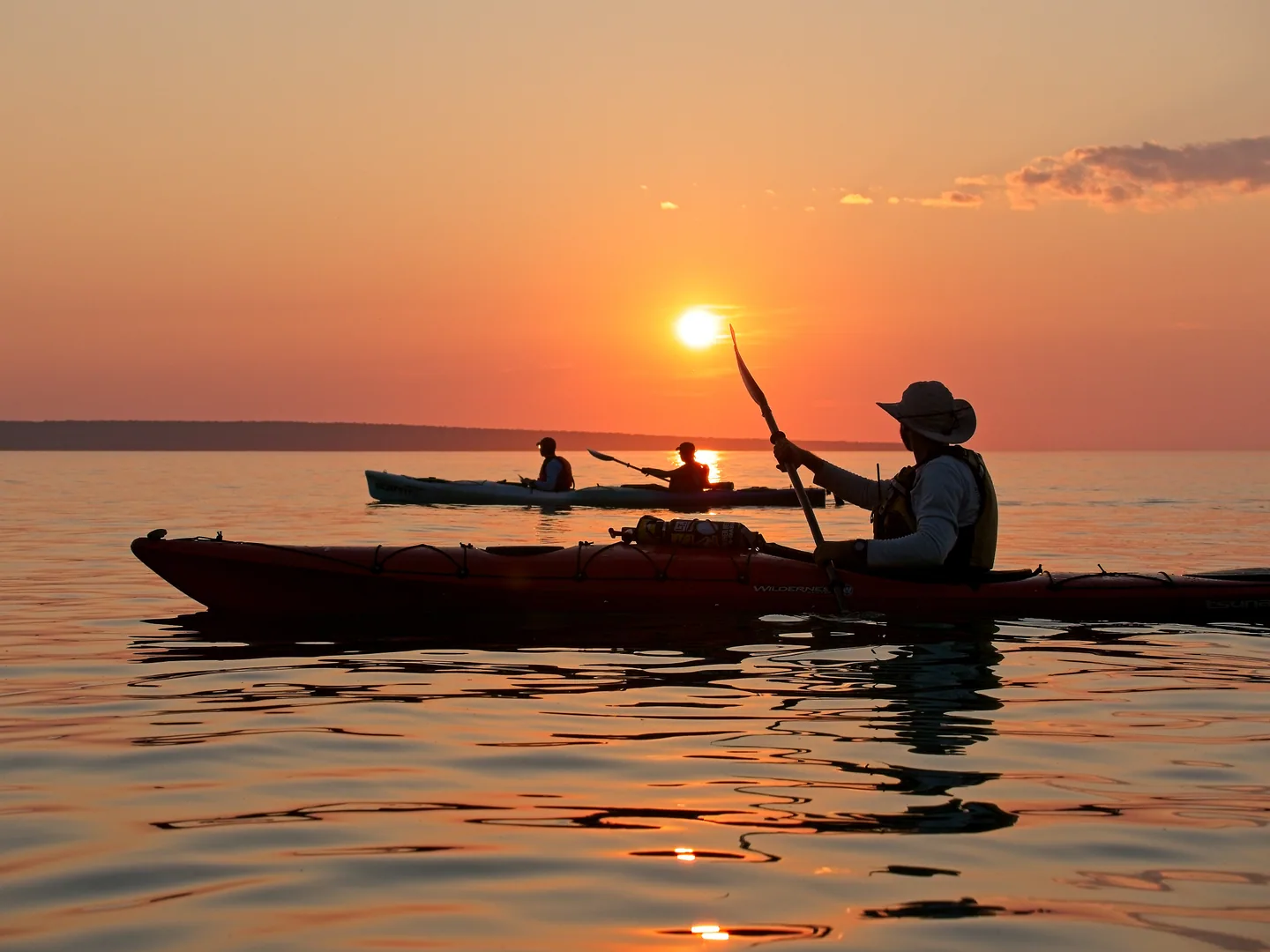 Kayakers crossing a glowing Lake Superior sunset