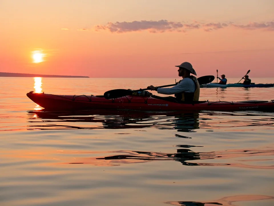 A single paddler glides through the sunset reflection as the lake settles for the night.